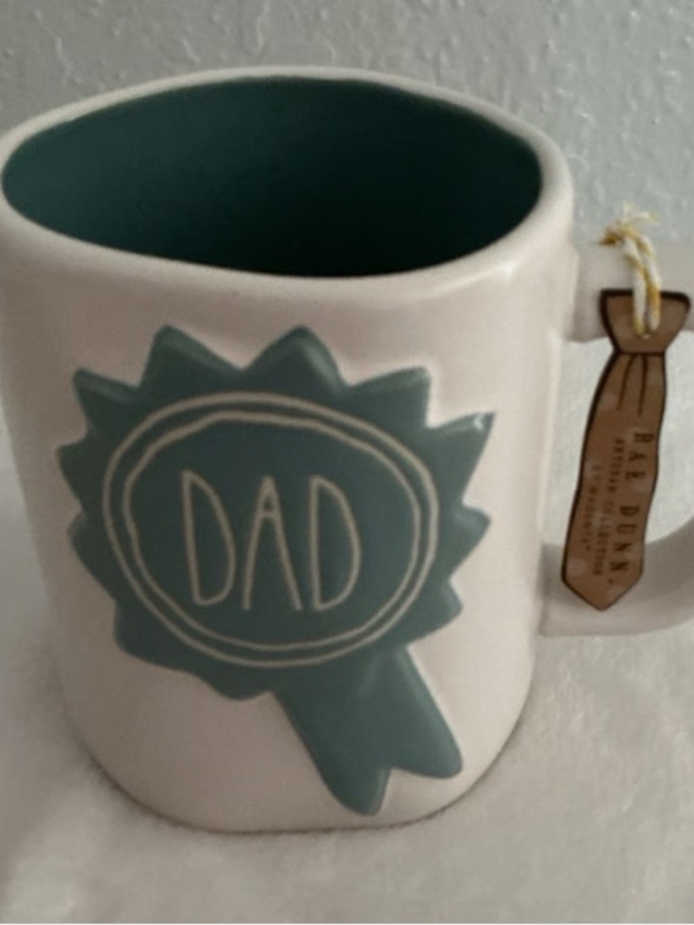 Rae Dunn White Ceramic Mug with Teal 'DAD' Ribbon Graphic